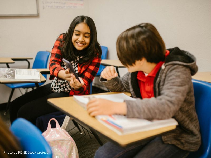 Student showing another student a cell phone while in class